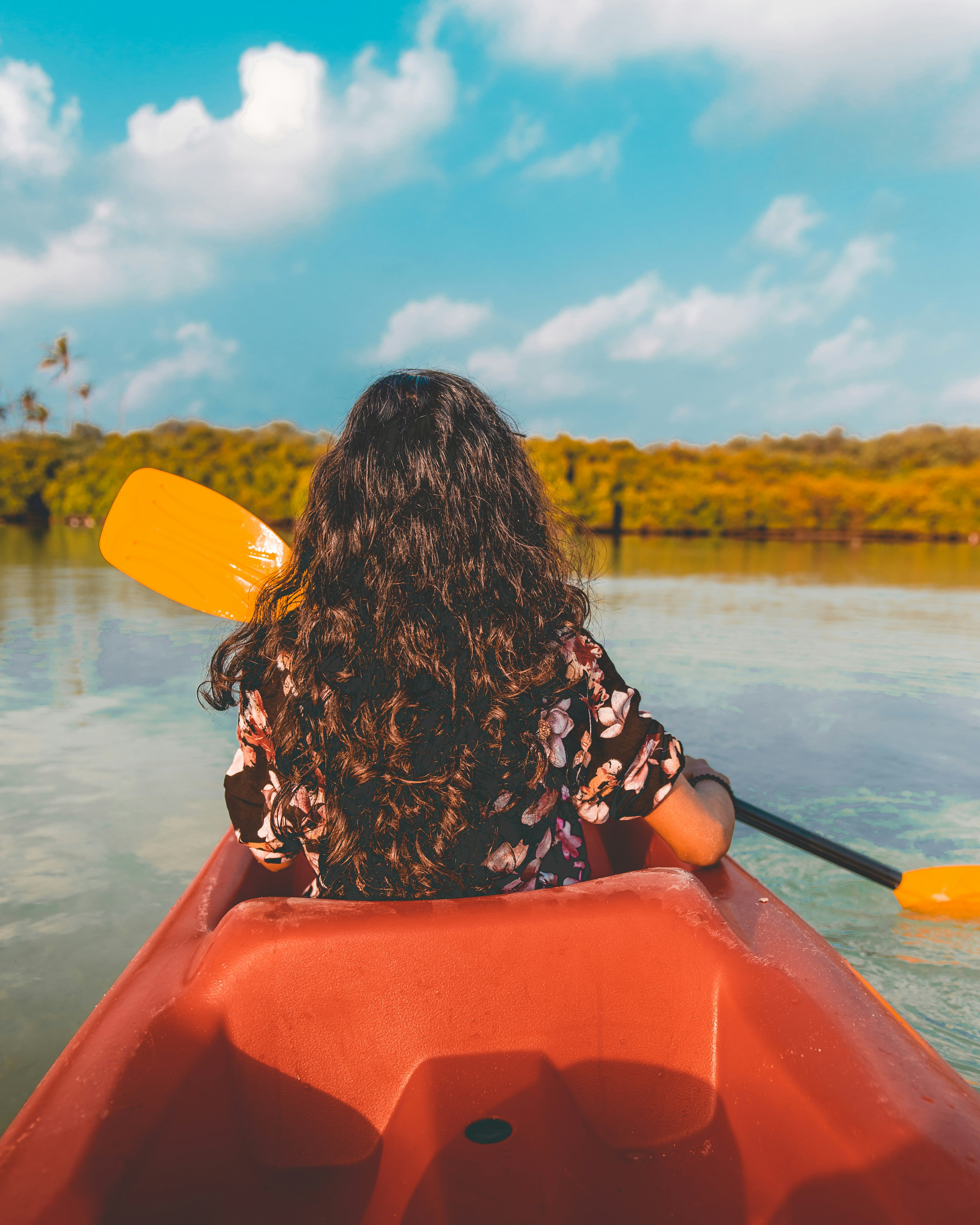 woman in black and white floral long sleeve shirt sitting on red kayak during daytime